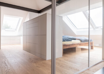 Sideboard freistehend als Raumtrenner Einfamilienhaus Gümligen, Schränke im Hintergrund eingepasst an Dachschräge. Sideboard und Schränke